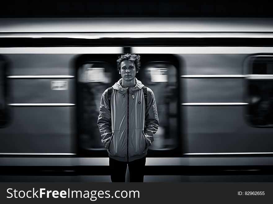 A young man standing at a metro station, a train passing behind him. A young man standing at a metro station, a train passing behind him.
