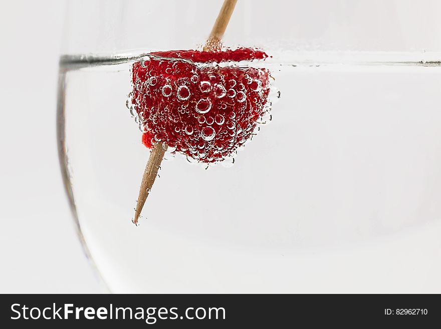 Red Raspberry on Water With Brown Stick