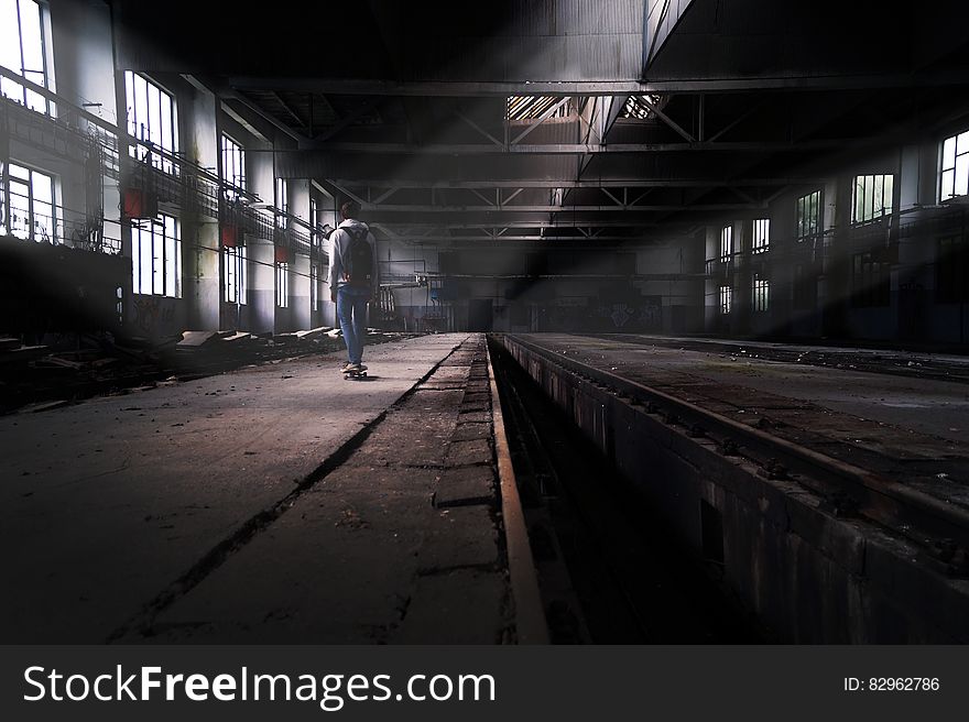 Rear view of skateboarder in abandoned urban factory building. Rear view of skateboarder in abandoned urban factory building.