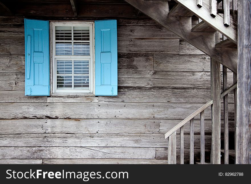 A wooden cabin with bright blue shutters on the window. A wooden cabin with bright blue shutters on the window.