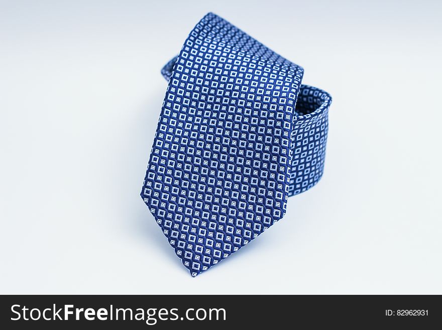 Closeup of fashionable blue silk tie with square patterns on light background.