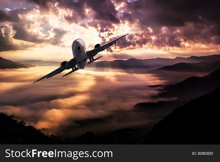 Airplane Flying Under White Clouds during Night Time