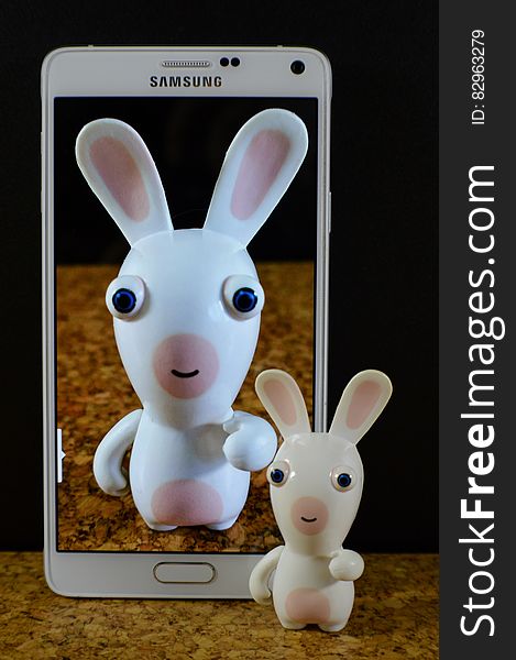 White and Pink Toy on Screen of White Samsung Smartphone