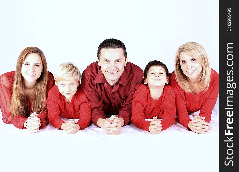 A family portrait with father, mother and three kids wearing red shirts.