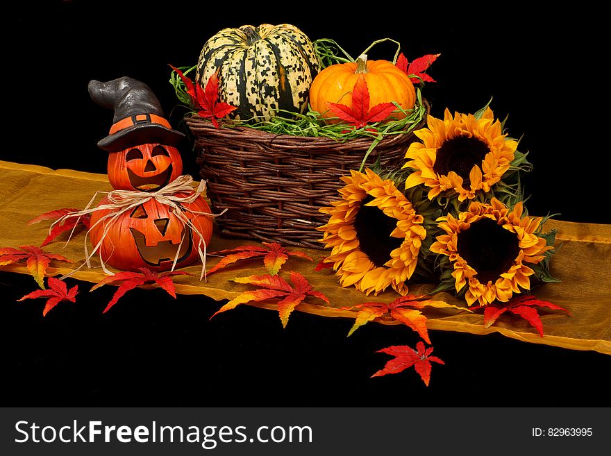 A basket of pumpkins and sunflowers with Halloween pumpkins on the side. A basket of pumpkins and sunflowers with Halloween pumpkins on the side.