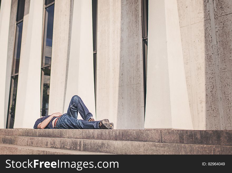 Man laying outside modern building on stone staircase on sunny day. Man laying outside modern building on stone staircase on sunny day.