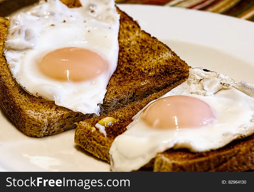 A pair of toasted slices of bread with fried egg on top. A pair of toasted slices of bread with fried egg on top.