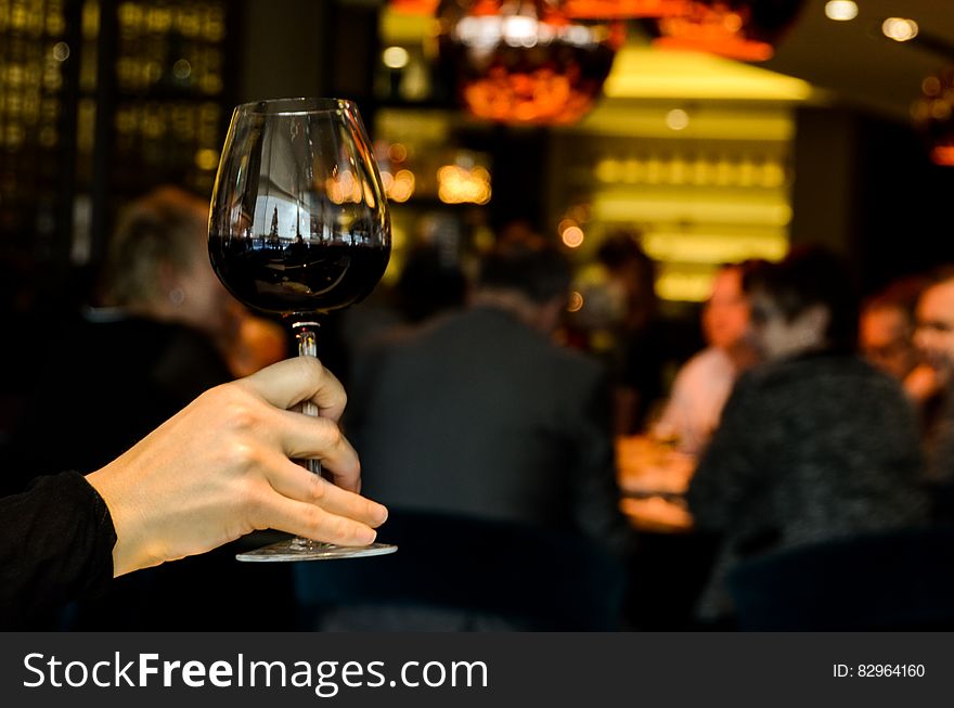 A woman holding up a full glass of red wine. A woman holding up a full glass of red wine.