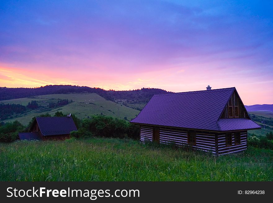 Wooden Cottage In Field At Sunset