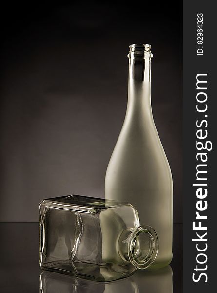 Full and transparent glass bottles on dark studio background with copy space.