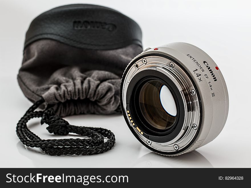 Closeup of Canon camera converter lens and case on white studio background.