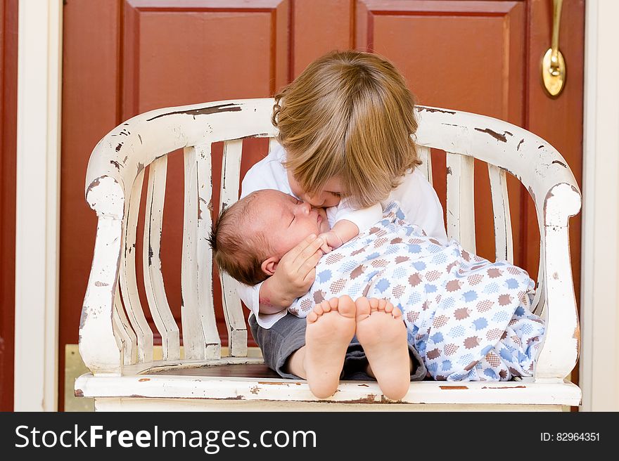 Portrait of young boy sat outside home cuddling newborn baby brother. Portrait of young boy sat outside home cuddling newborn baby brother.