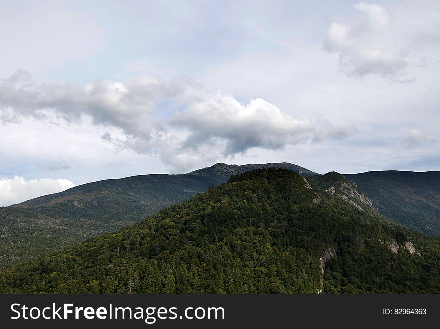 Scenic view of forest covered mountain landscape with cloudscape background.