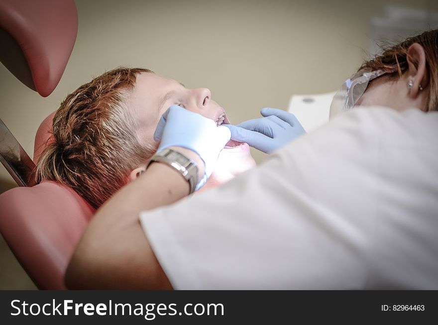 Dentist Woman Wearing White Gloves And White Scrubsuit Checking Boy&x27;s Teeth