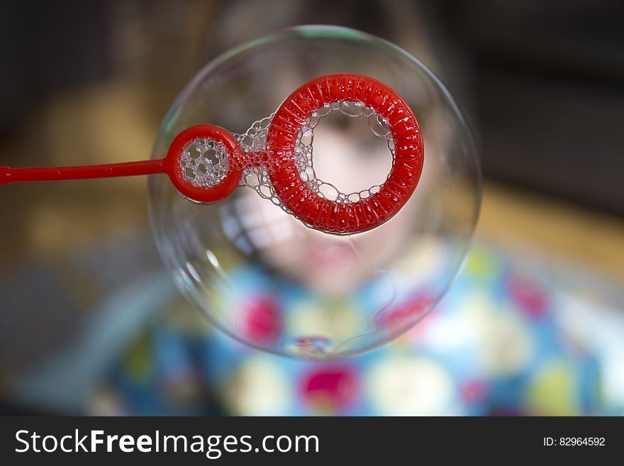 Close up of soap bubble on red wand.