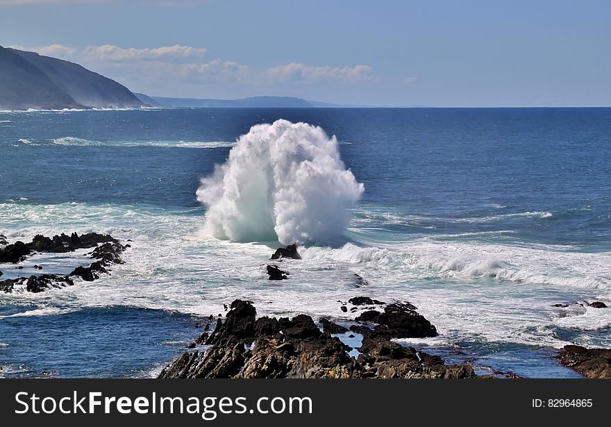 Waves breaking along rocky shores on sunny day with blue skies. Waves breaking along rocky shores on sunny day with blue skies.