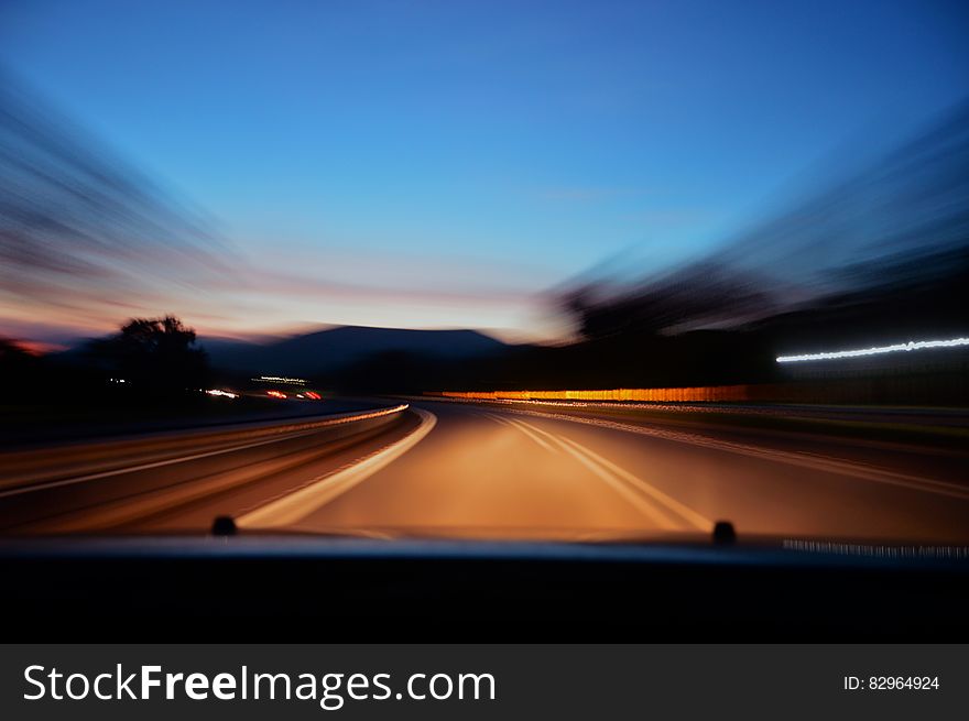 Blur of car driving on empty roadway at sunset. Blur of car driving on empty roadway at sunset.