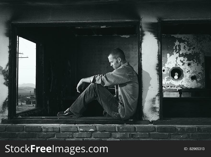 Man sitting outdoors in urban decay in black and white. Man sitting outdoors in urban decay in black and white.