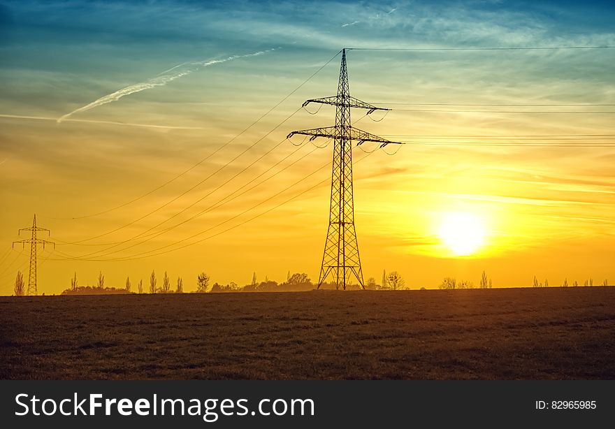 Electric pole in field at sunset