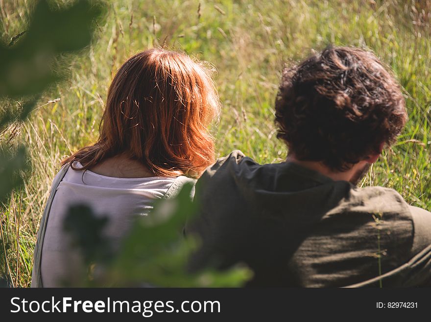 People Photography of Man and Woman Sitting on Green Grass Field