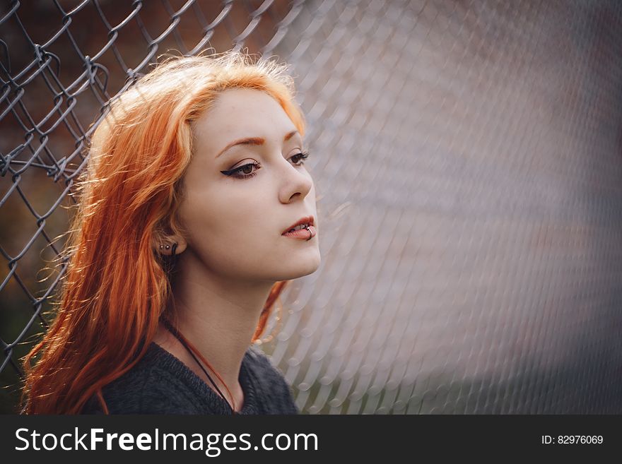Woman Leaning on Gray Chain Link Fence