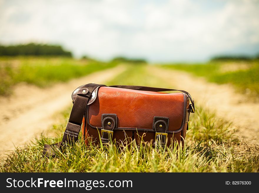 Vintage leather bag on dirt country lane on sunny day. Vintage leather bag on dirt country lane on sunny day.