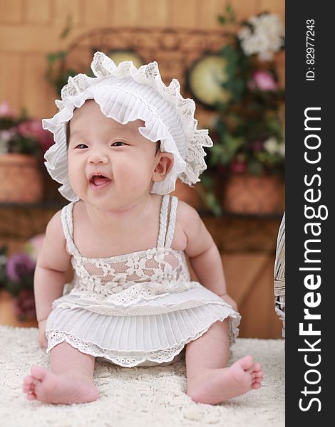 Baby in White Dress With White Headdress