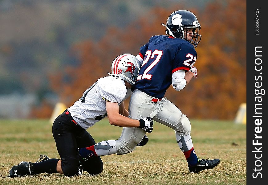 Football Player in White Trying to Stop a Player in Blue