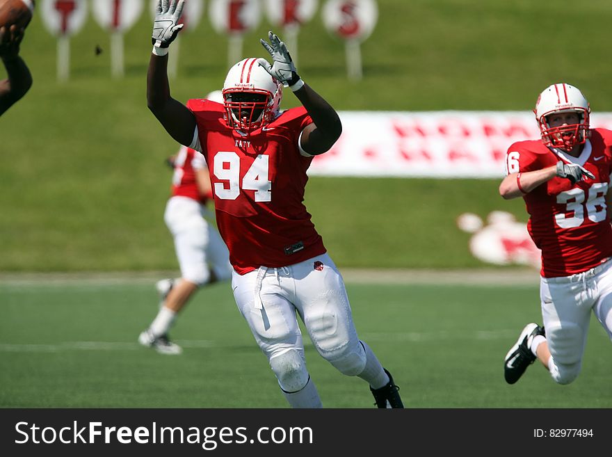 Person Wearing Nfl Suit With a Man Wearing White and Red Nfl Suit Running on Green Grass Field