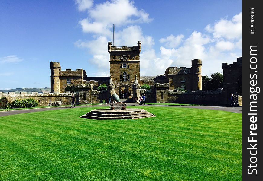 Castle on green lawn against blue skies with white clouds.