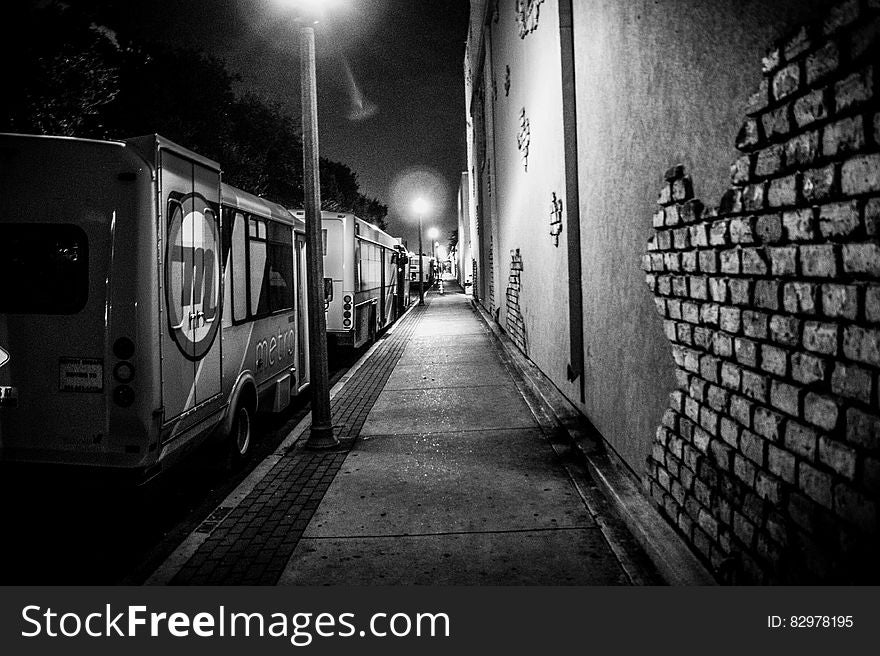 Urban alleyway with trucks parked along sidewalk with streetlamps in black and white. Urban alleyway with trucks parked along sidewalk with streetlamps in black and white.