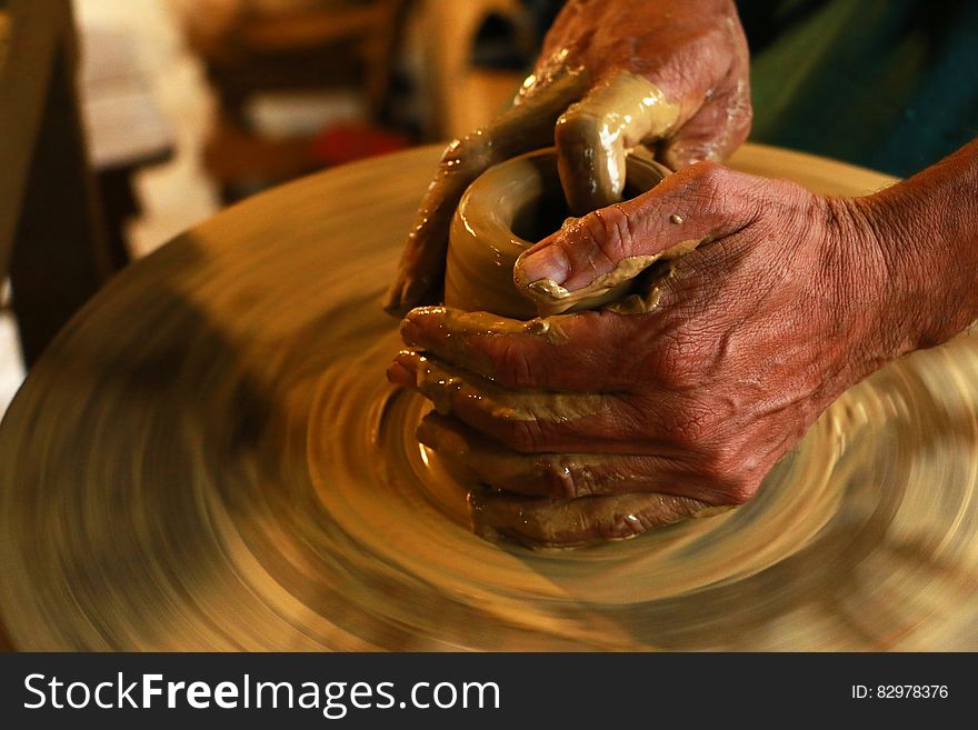 A close up of hands shaping a piece of pottery.