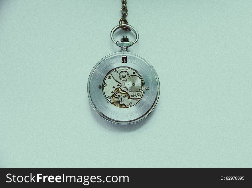 An old fashioned hanging watch on a pale blue background.