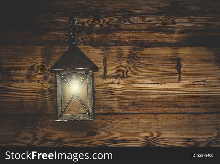 An old fashioned lantern hanging on a wooden wall.