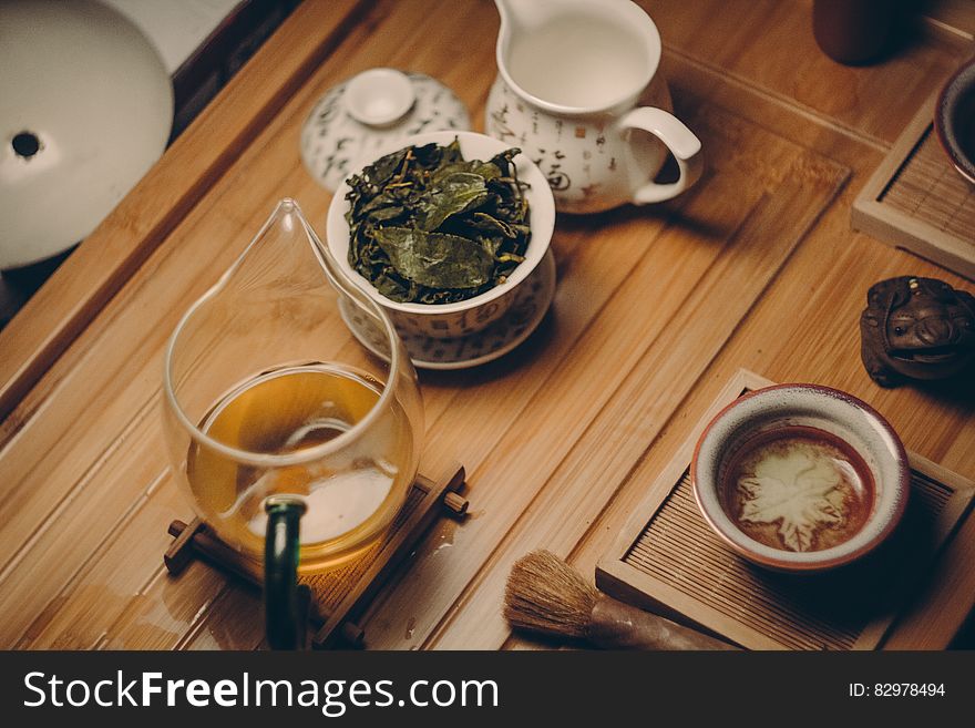 White Ceramic Teapot Beside Cup With Leaves