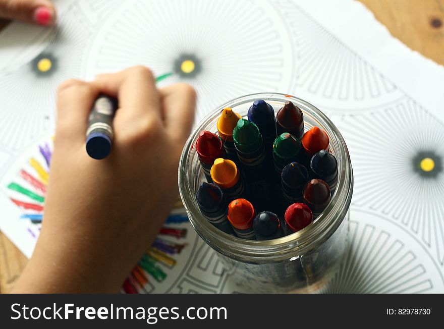 Hand of child using crayons to color printed page. Hand of child using crayons to color printed page.