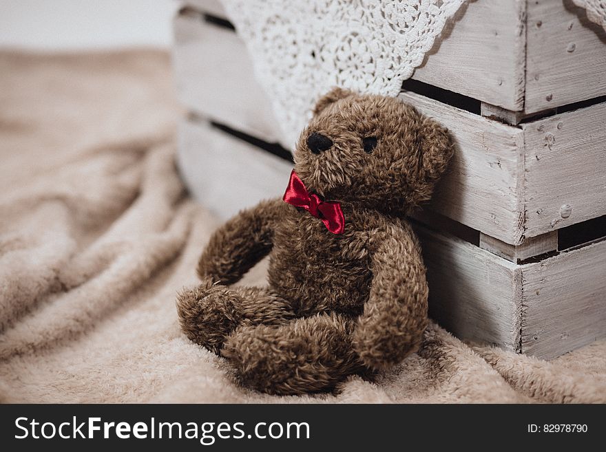 A teddy bear leaning on a wooden crate.