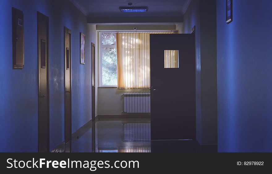 A dark hallway of a hospital or sanitarium with one door open.