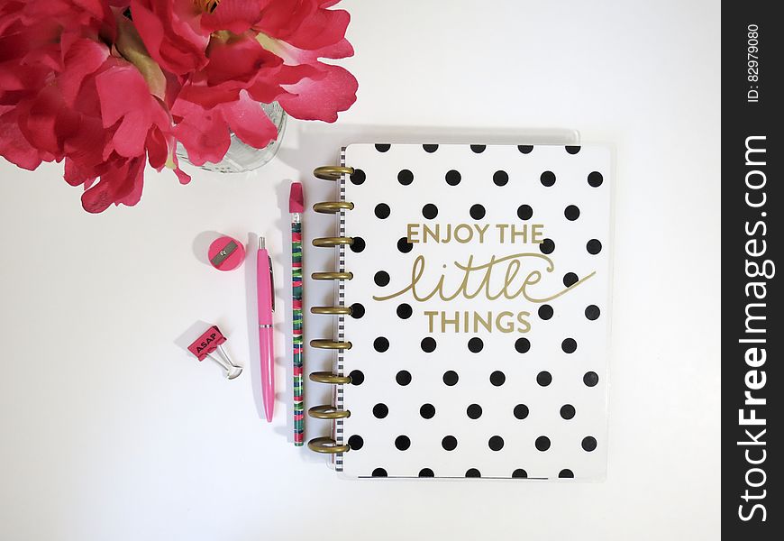 A polka dot notebook with writing supplies and a flower bouquet.