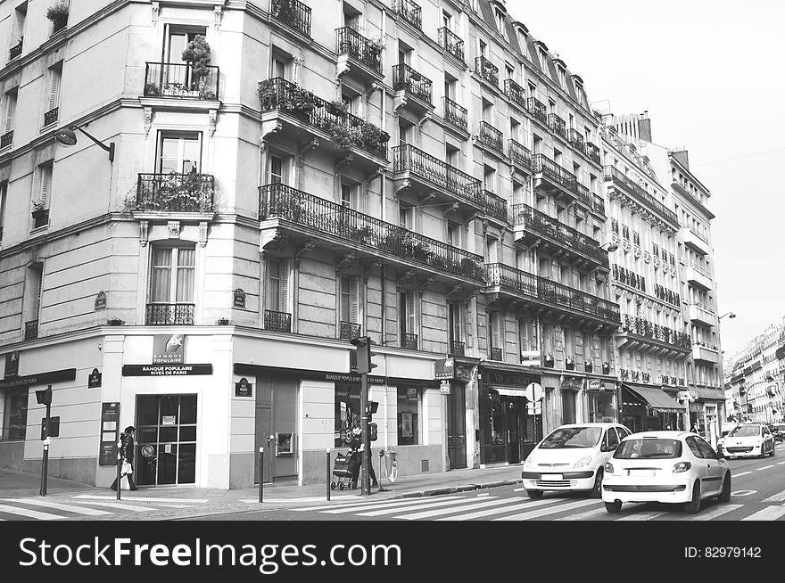 Exterior of city buildings along streets with traffic in black and white. Exterior of city buildings along streets with traffic in black and white.