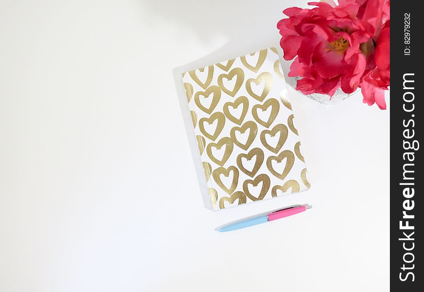 A notebook with hearts on the cover and red bouquet of flowers. A notebook with hearts on the cover and red bouquet of flowers.