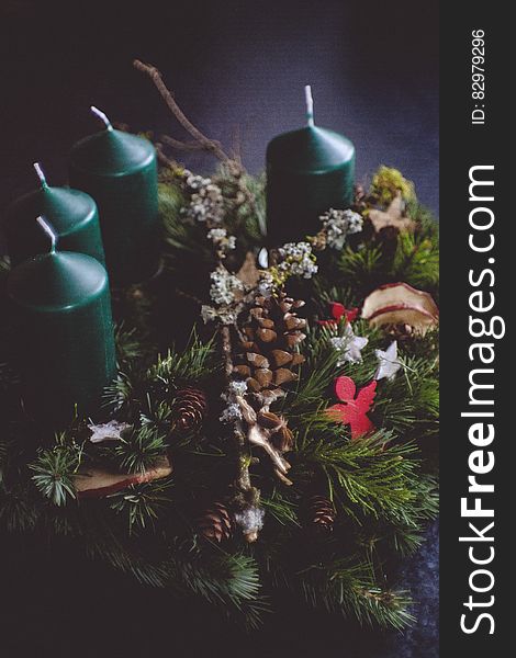 A Christmas wreath with conifer branches and cones and candles in the background. A Christmas wreath with conifer branches and cones and candles in the background.