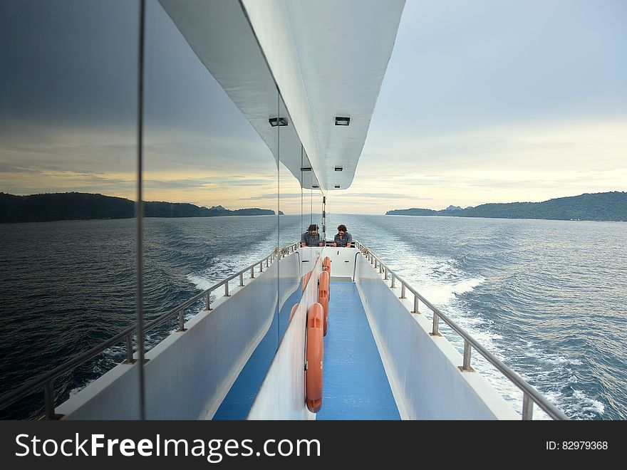 Two people sitting on a sailboat deck. Two people sitting on a sailboat deck.