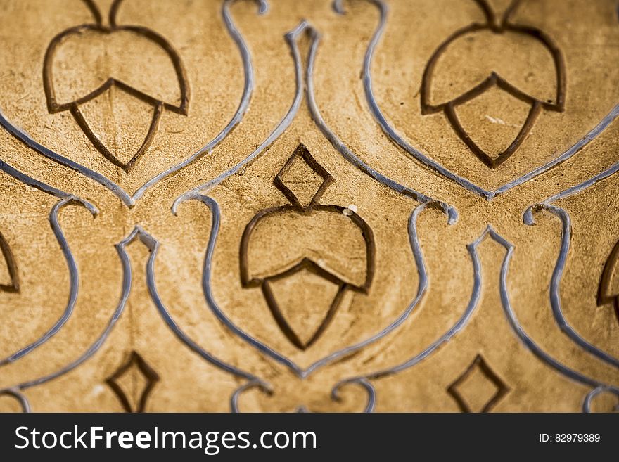 Abstract pattern of an acorn shape repeated and engraved into the surface of beige tile. Additional swirls around the acorns frame and emphasize the subject. Abstract pattern of an acorn shape repeated and engraved into the surface of beige tile. Additional swirls around the acorns frame and emphasize the subject.