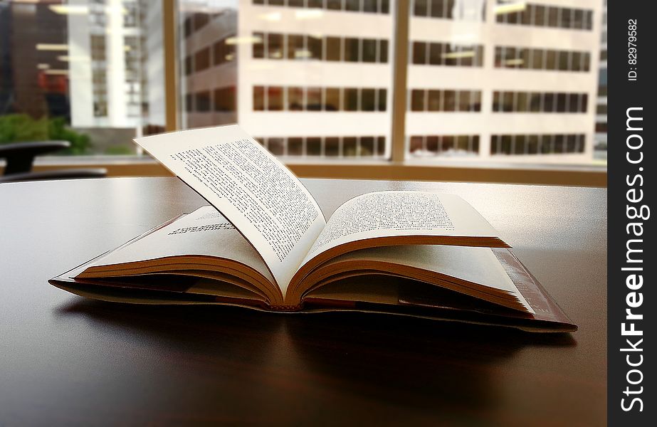 Open book on desktop next to window in city office.