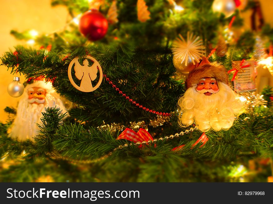 Close up of Santa faces and angels on Christmas tree with lights. Close up of Santa faces and angels on Christmas tree with lights.