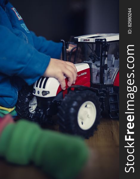 Close up of child playing on floor with toy tractor. Close up of child playing on floor with toy tractor.