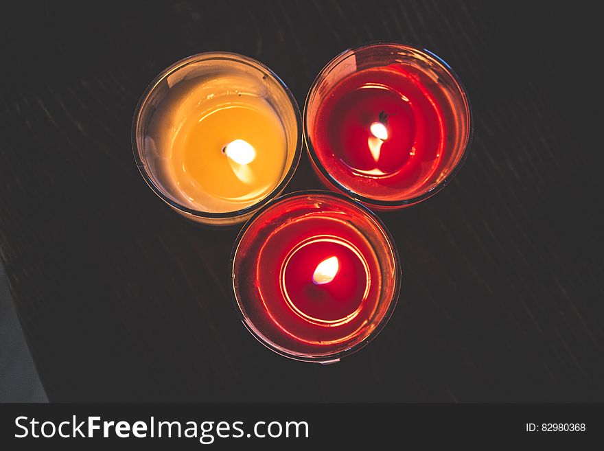 Lighted Red Wax Candle on Clear Drinking Glass