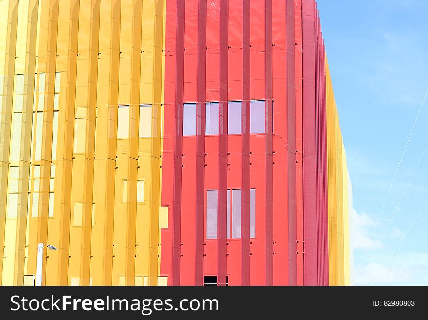 Multistory building of contemporary architectural design with steel construction, in pink and yellow colors, pale blue sky. Multistory building of contemporary architectural design with steel construction, in pink and yellow colors, pale blue sky.