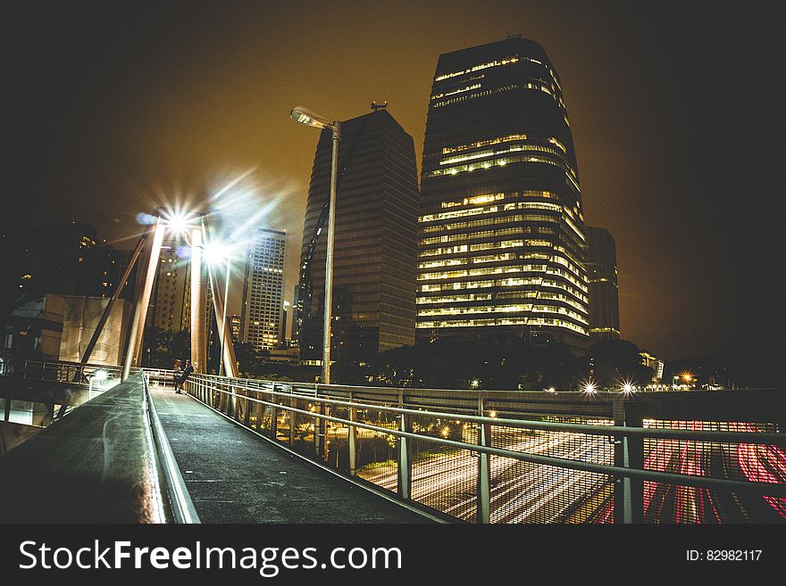 A night view of a city with traffic passing under a bridge. A night view of a city with traffic passing under a bridge.